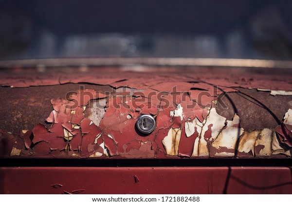The texture of the old red trunk of a car with\
cracked multi-layer paint.