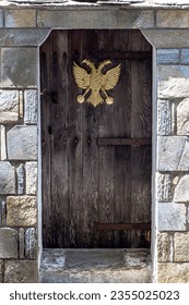 The texture, pattern. The background old beige wall made of natural stone with wooden door with double-headed eagle