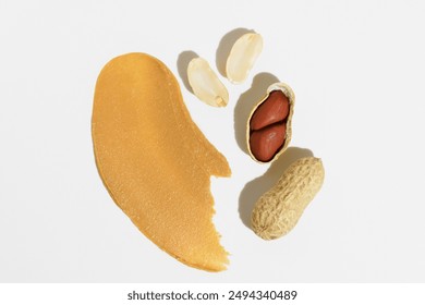Texture of peanut paste and whole nuts without shell and in shell on white isolated background. Concept of peanut butter for breakfast bread, healthy snack and source of protein