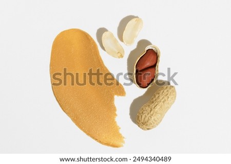 Texture of peanut paste and whole nuts without shell and in shell on white isolated background. Concept of peanut butter for breakfast bread, healthy snack and source of protein