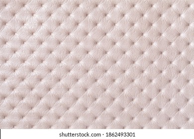 Texture of pearl beige leather background with capitone pattern, macro. Cream textile of retro Chesterfield style. Vintage fabric backdrop.