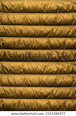Texture of puffer, padded, down jacket. Background of urban winter outfit. Quilted pattern.