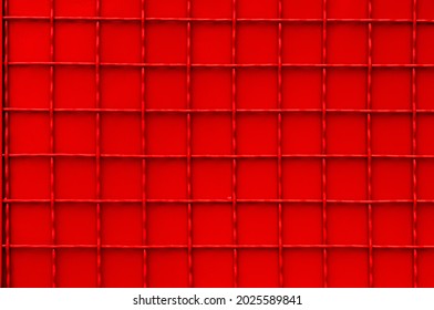 Texture Of Red Checkered Metal Fence. Red Metal Sheet With Gauze For Background. Urban Element Of A Red Metal Fence With Square Weave.