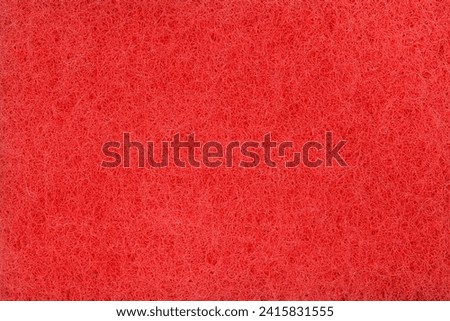 Texture of the red synthetic material of the kitchen hard urethane abrasive cleaning sponge, top view close-up

