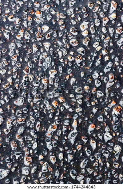 Texture of the road\
surface after rain with foaming water from passing cars that flows\
between the pattern of various stones that make up the asphalt\
invoice, close-up,\
background