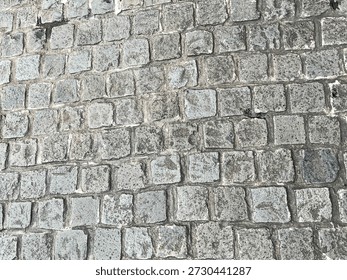 Texture of a rough aged pavement constructed with square blocks. It's detailed and shows signs of wear and time. Suitable for background and overlay use.