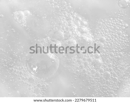 The texture of soap bubbles in close-up. Bubble bath. Gel for washing or washing hands. Blue background with bursting bubbles.