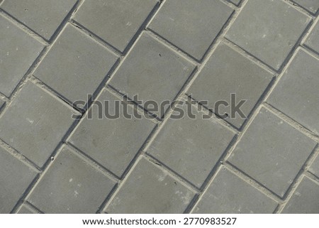Texture of square brick-like gray concrete pavement with stack bond layout