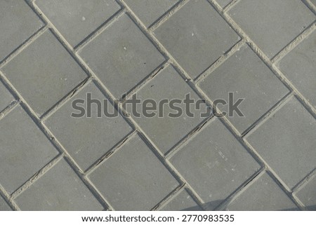 Texture of square brick-like gray concrete pavement with stack bond layout