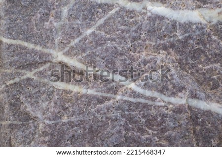 The texture of the stone with veins white veins. Dark background, natural stone surface.