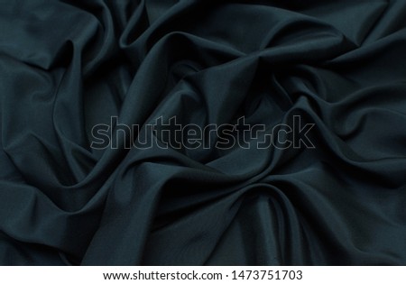 The texture of the synthetic fabric is dark green. Background, pattern.