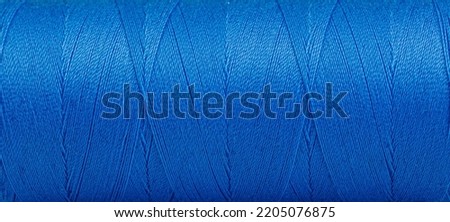 Texture of threads in a spool of blue color on a white background close-up