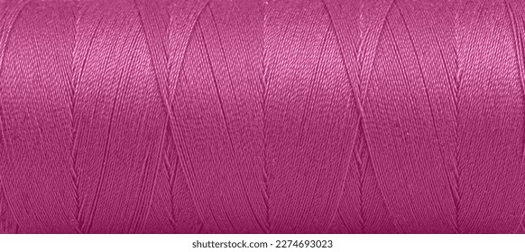 Texture of threads in a spool of pink color on a white background close-up