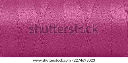 Texture of threads in a spool of pink color on a white background close-up