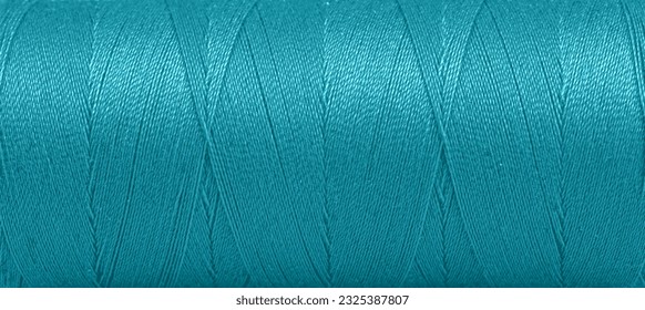 Texture of threads in a spool of turquoise color on a white background close-up