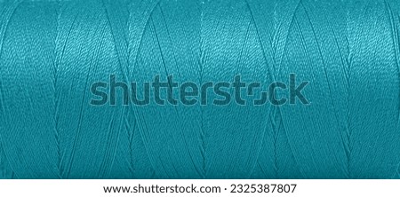Texture of threads in a spool of turquoise color on a white background close-up