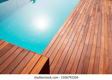 Texture with tiled wooden decorative planking, hardwood ipe pool deck shining sun reflecting on the water