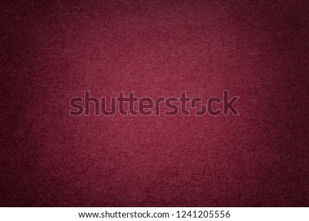 Texture of vintage dark red paper background with vignette. Structure of dense maroon kraft cardboard with frame. Felt wine gradient backdrop closeup.