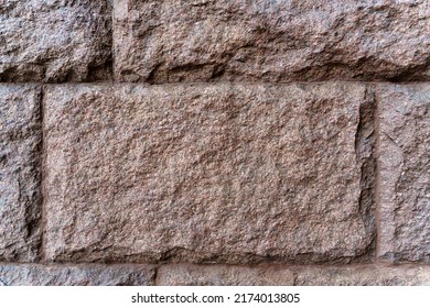 Texture. The wall is made of rectangular blocks of red granite.