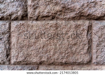 Texture. The wall is made of rectangular blocks of red granite.