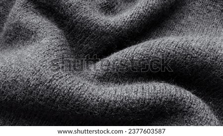 Texture of warm knitted wool fabric. Winter clothes. Natural wool, black wool fabric.