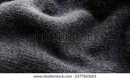 Texture of warm knitted wool fabric. Winter clothes. Natural wool, black wool fabric.