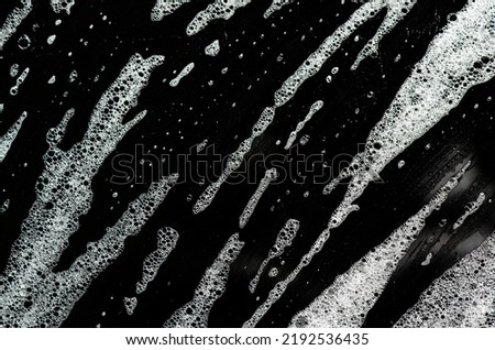 Texture of white foam on a black background. Cleansing mousse for the face or shaving foam or washing powder. Closeup