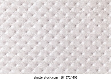 Texture of white leather background with capitone pattern, macro. Pearl textile of retro Chesterfield style. Vintage fabric backdrop.