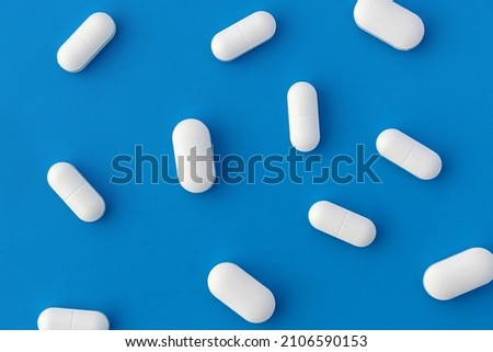 Texture of white oblong tablets lying on a blue background.