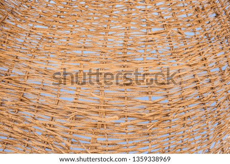 Texture of woven straw twigs through which you can see the blue sky