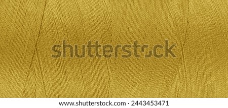 Texture of yellow color threads in spool close up, macro. Wide banner, header of sewing threads bobbin abstract background, wallpaper, backdrop.