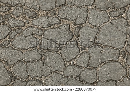 Textured backdrop. Web of cracks. Mosaic texture, background of an old, cracked road. An old asphalt surface, background. Detailed texture of the bitumen close-up. Screen short. Road foundation