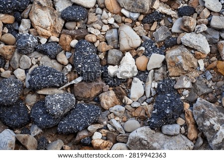 A textured background composed of various sizes and colors of rocks, pebbles, and coarse aggregate materials