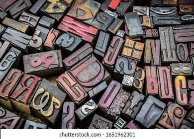 A textured background of old, used, wooden type-setting letter blocks with various fonts, upper- and lowercase, antique letters, all shapes and sizes. 