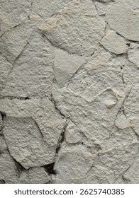 Textured close-up of light gray limestone rock surface. Natural, rough texture with visible cracks and variations. Ideal for backgrounds, geological studies, or construction material visuals