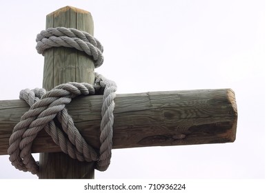 Textured Coarse Rope Wrapped Around Wooden Pillar That Anchors A Fishing Boat In Northern Minnesota On A Lake With A Cabin. 
