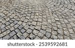 Textured cobblestone pavement in a circular pattern. Ideal for backgrounds in design projects or as a natural surface in urban photography.