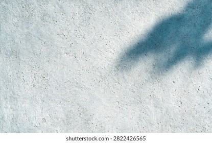 A textured concrete surface with a soft shadow cast, creating a subtle interplay of light and form, ideal for backgrounds and abstract designs.