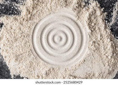 A textured flour background with a circular pattern. The background is off-white, with off-white flour creating a rustic, grainy texture. Powder texture background. Beige powder on black background.
