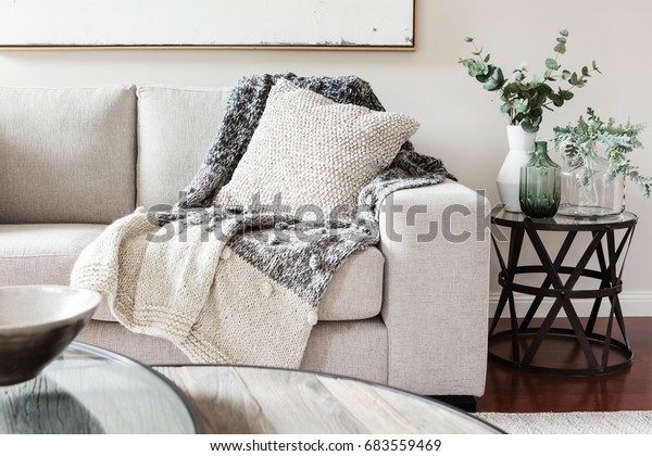 Textured layers interior styling of cushion sofa\
and throw in neutral\
colors