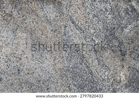 Textured stone background featuring a blend of grey, tan, reddish-brown, with fine white flecks, natural grain patterns, speckles, and subtle surface cracks.