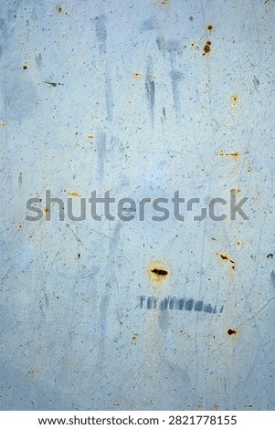 Textured surface with light blue paint and rust spots.