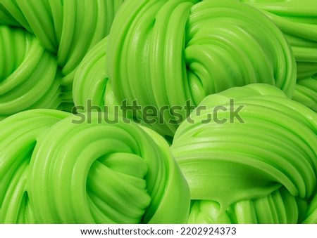 Textured volumetric molded slime for hands. Stretchable antistress toy. Swirl fluffy slime green background