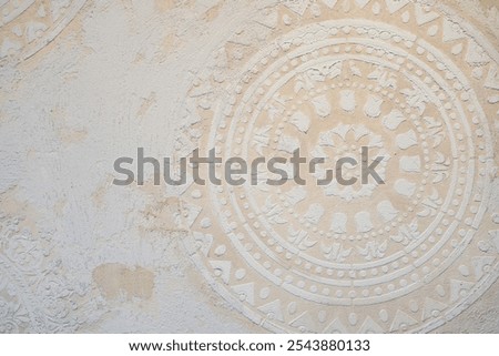 Textured wall with intricate mandala pattern in soft beige tones, creating a rustic, bohemian, and earthy background for decor or design projects.