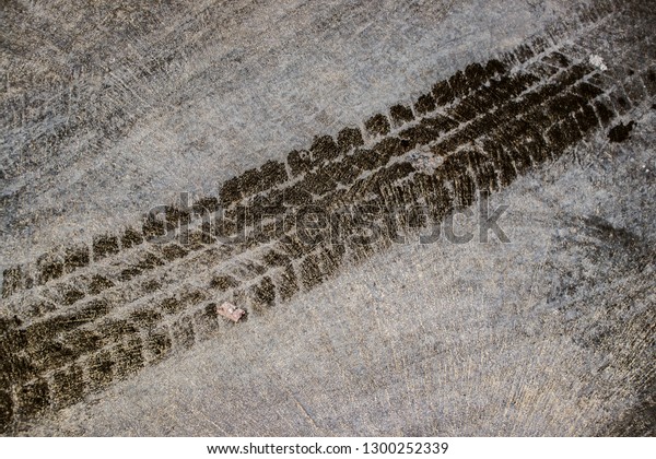 Textured of wet tire marks or footprint on the\
dirty concrete or cement floor in the car park as grunge background\
and backdrop