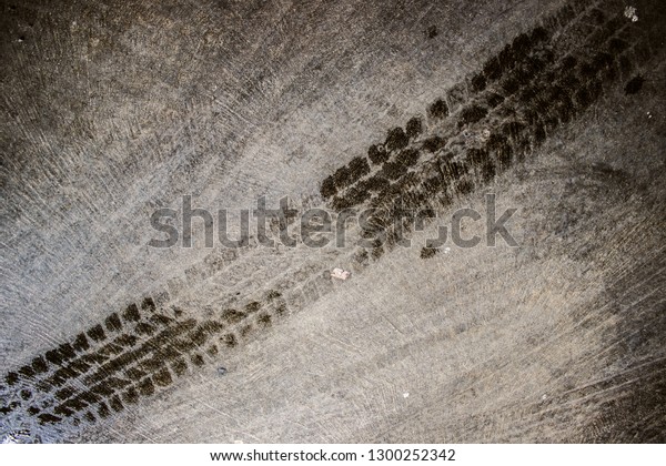 Textured of wet tire marks or footprint on the\
dirty concrete or cement floor in the car park as grunge background\
and backdrop
