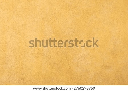 Textured yellow plaster wall background with warm ochre tones with high resolution. Top view. Copy space.