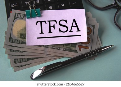 TFSA (Tax Free Savings Account) - Acronym On A White Piece Of Paper Fixed On Banknotes Against The Background Of A Calculator, Glasses And Pen. Business And Finance Concept