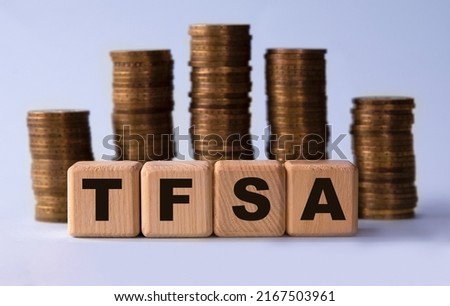 TFSA (Tax free savings account) - acronym on wooden cubes on the background of stacks of coins. Business concept