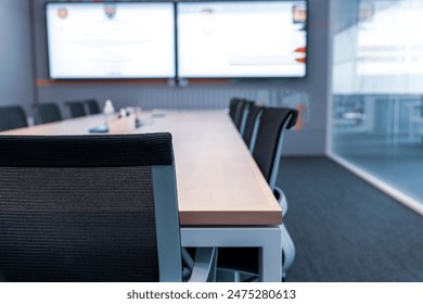 Th showcases a modern, professional conference room setting.Room features a large wooden table surrounded by black mesh office chairs, indicating a space designed for meetings or collaborative work.  - Powered by Shutterstock